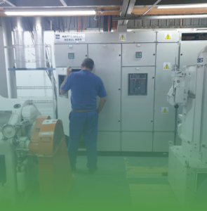 Okuni Africa technician performing maintenance on an industrial electrical control panel and switchboard.