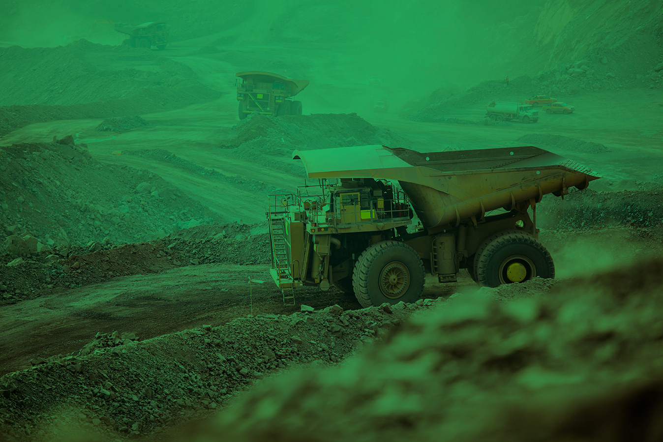 Heavy mining haul trucks operating in a dusty open-pit excavation site, representing Okuni Africa's large-scale industrial operations.